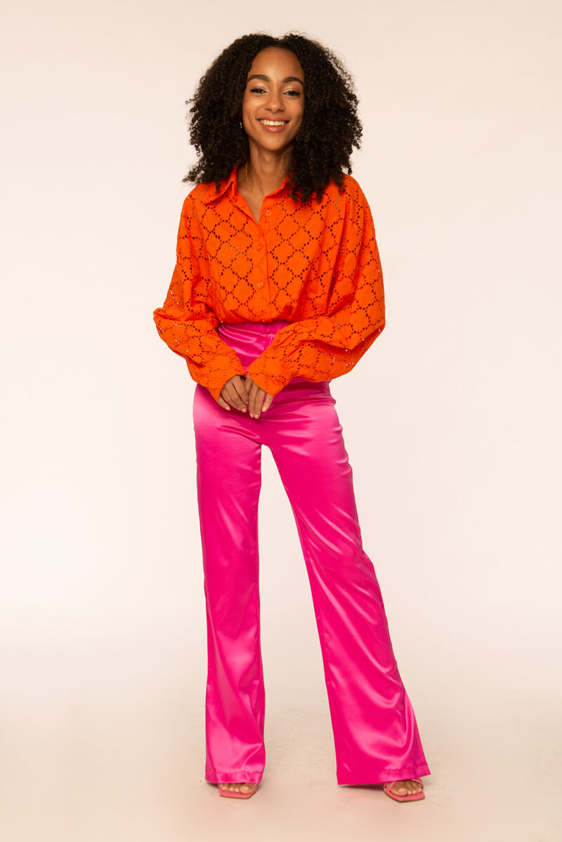 Trendy dames outfit met een roze satijnen broek met oranje blouse