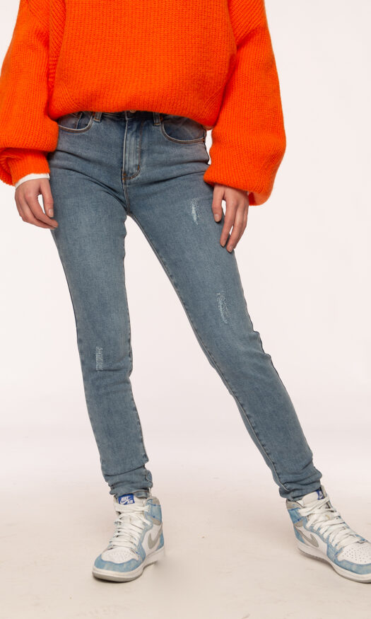 Blauwe jeans met destroyed effect met oranje trui