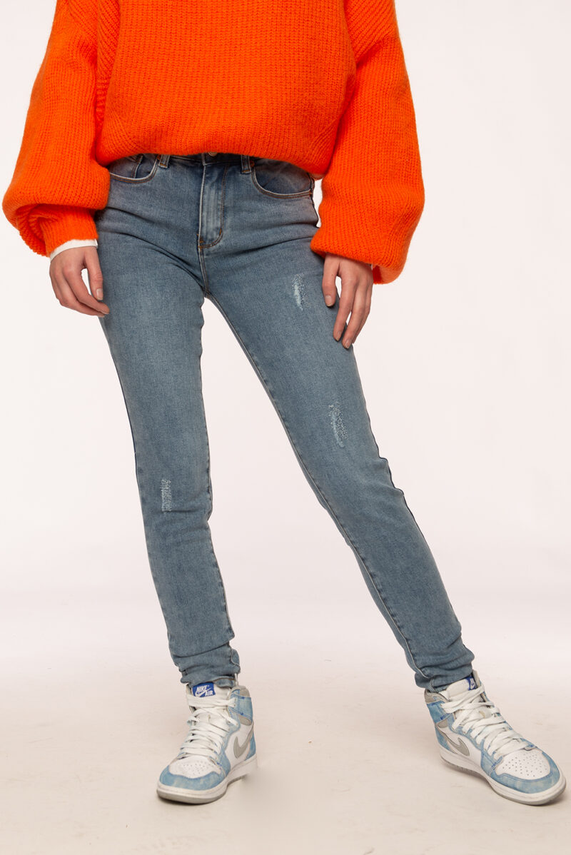 Blauwe jeans met destroyed effect met oranje trui